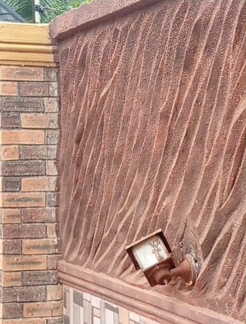 Wall with a flowing ridged texture finish in terracotta beside a brick pillar