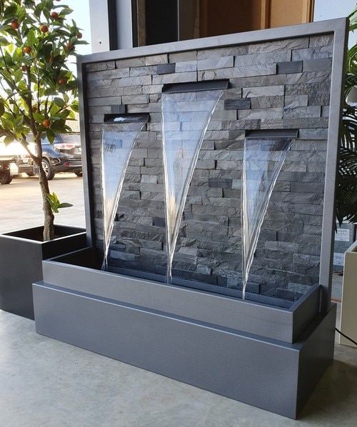 Grey stone-clad fountain with three curved water spouts