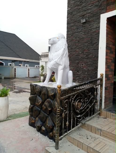 White lion statue beside wrought-iron railings at a house entrance