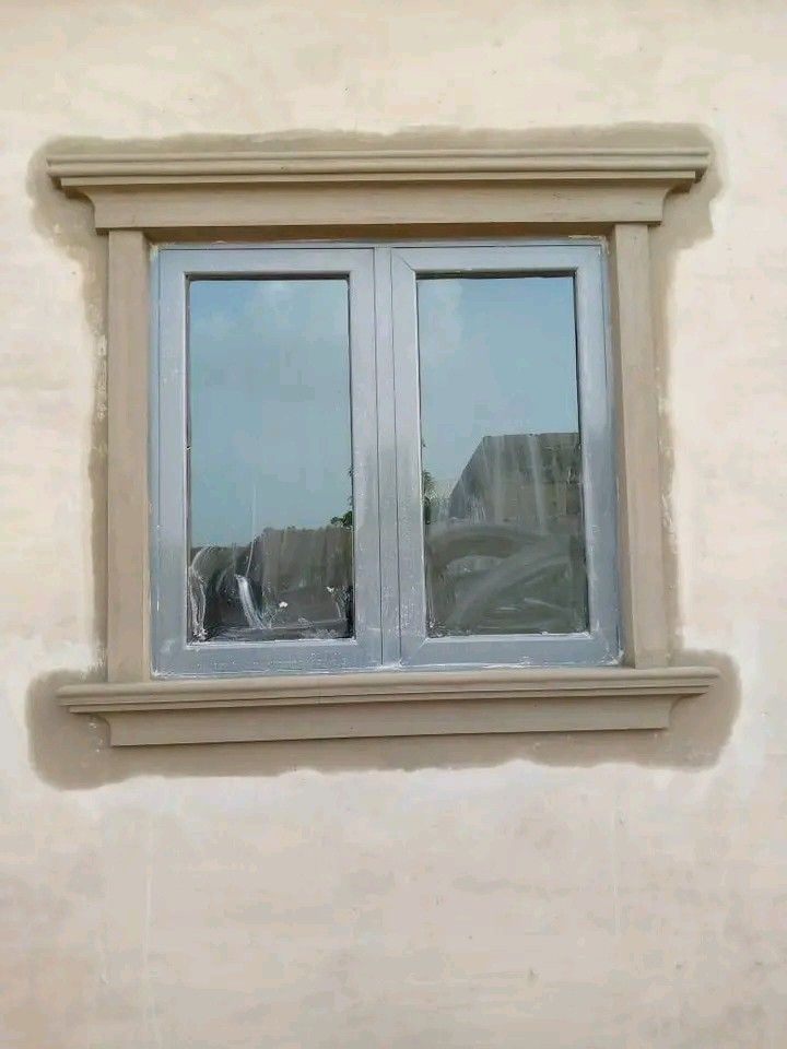 Moulded window hood with cornice and sill around a two-pane window