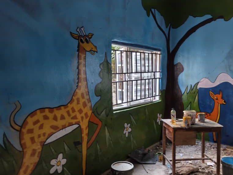 Classroom mural of a giraffe and a deer in a savannah scene
