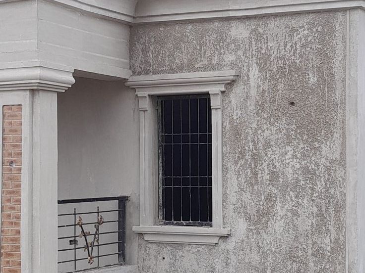 Moulded window hood and frame on a textured house wall